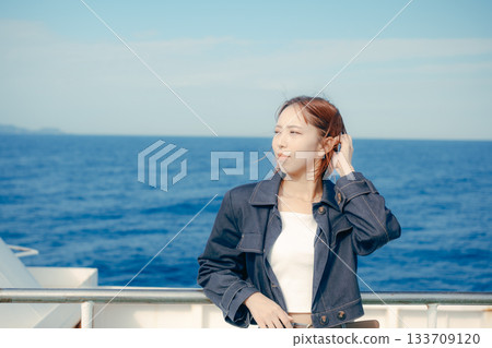 旅行場景：一位二十多歲的女子在渡輪甲板上感受海風。 133709120