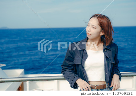 旅行場景：一位二十多歲的女子在渡輪甲板上感受海風。 133709121