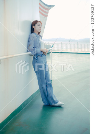 Travel scene of a woman in her twenties feeling the sea breeze on the deck of a ferry 133709127