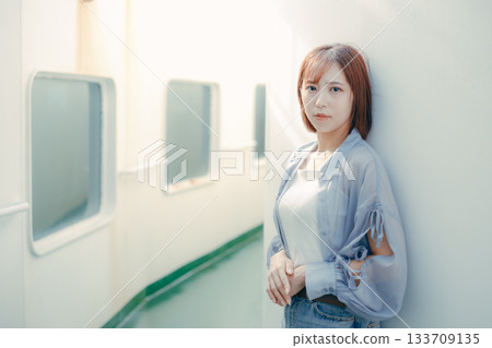 Travel scene of a woman in her twenties feeling the sea breeze on the deck of a ferry Travel scene of a woman in her twenties feeling the sea breeze on the deck of a ferry 133709135