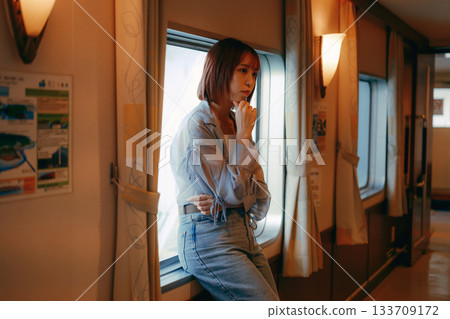 Travel scene of a woman in her twenties standing by the window on a ferry Travel scene of a woman in her twenties standing by the window on a ferry 133709172