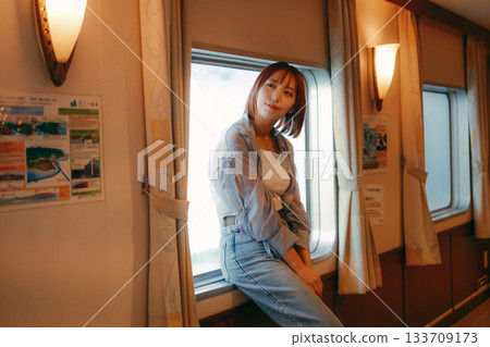 Travel scene of a woman in her twenties standing by the window on a ferry Travel scene of a woman in her twenties standing by the window on a ferry 133709173