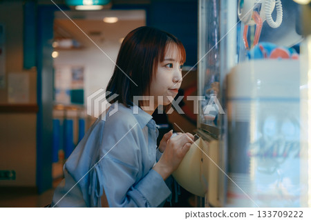 A woman in her 20s is engrossed in a crane game and looks at her boyfriend. A woman in her 20s is engrossed in a crane game and looks at her boyfriend. 133709222