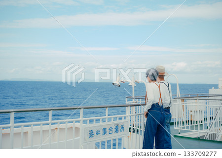 Travel scene with senior couple pointing at the scenery on the deck of a ship Travel scene with senior couple pointing at the scenery on the deck of a ship 133709277