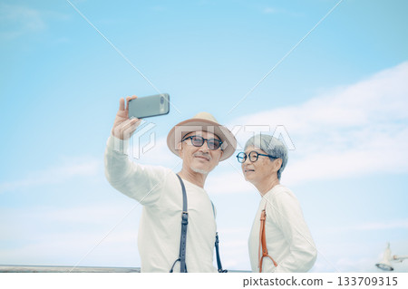 Travel scene of a senior couple taking a selfie on the deck of a ship Travel scene of a senior couple taking a selfie on the deck of a ship 133709315