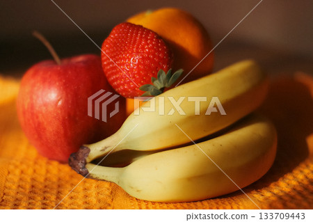 Assorted Fresh Fruits on Orange Textured Cloth Assorted Fresh Fruits on Orange Textured Cloth 133709443