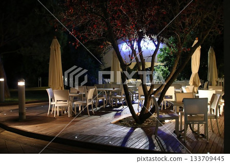 Outdoor Dining Area at Night with Closed Umbrellas and Ambient Lighting Outdoor Dining Area at Night with Closed Umbrellas and Ambient Lighting 133709445