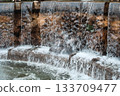 Water cascading over stone spillway into foamy pool 133709477