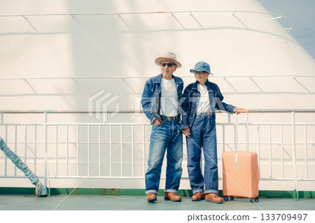 一對老年夫婦帶著行李箱,在渡輪甲板上享受旅程。 一對老年夫婦帶著行李箱,在渡輪甲板上享受旅程。 133709497