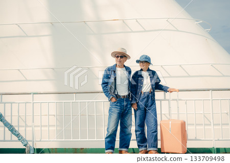 一對老年夫婦帶著行李箱，在渡輪甲板上享受旅程。 133709498