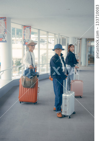 Portrait of a senior couple and a young woman standing side by side with suitcases Portrait of a senior couple and a young woman standing side by side with suitcases 133710083