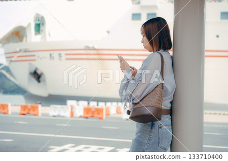 A woman looking at her smartphone at the ferry terminal 133710400