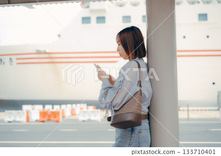 A woman looking at her smartphone at the ferry terminal A woman looking at her smartphone at the ferry terminal 133710401