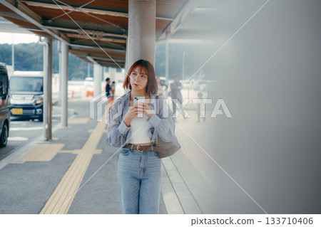 一名女子在渡輪碼頭看著她的智慧型手機。 一名女子在渡輪碼頭看著她的智慧型手機。 133710406