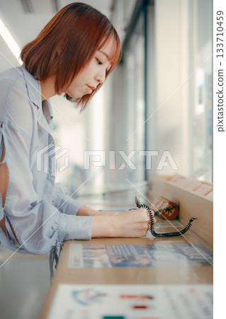 一位女士正在櫃檯填寫表格。 133710459