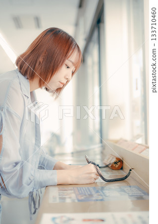 A woman filling out paperwork at the counter 133710460
