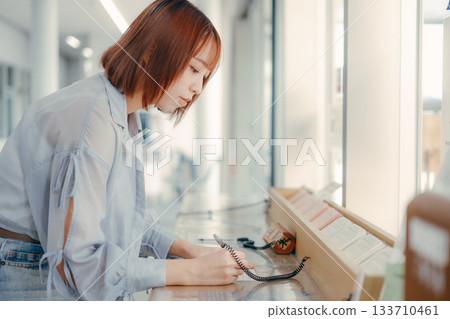 A woman filling out paperwork at the counter 133710461