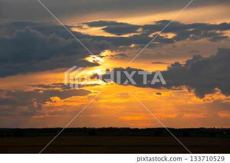 Dramatic orange sunset light in the sky over autumn prairies. 133710529