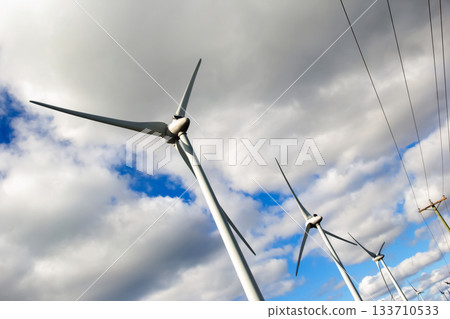 Windmills and power lines in the background of blue sky. Windmills and power lines in the background of blue sky. 133710533
