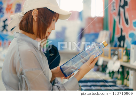 一位女士拿起一個瓶子，在店內仔細端詳。 133710909