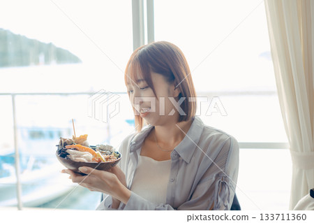 旅行途中,手裡拿著一碗海鮮。 旅行途中,手裡拿著一碗海鮮。 133711360
