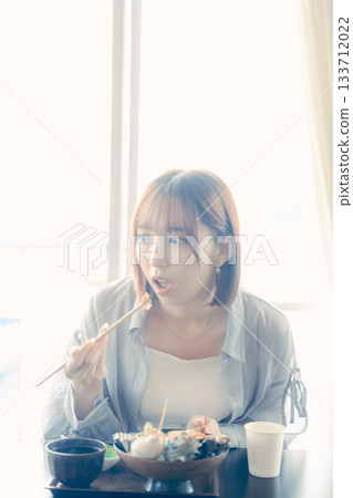 一位二十多歲的女子正在吃海鮮飯 一位二十多歲的女子正在吃海鮮飯 133712022