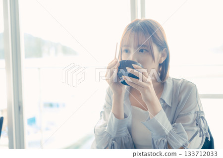 一位二十多歲的女子正在吃海鮮飯 133712033