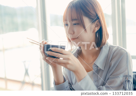 A woman in her twenties eating a seafood bowl A woman in her twenties eating a seafood bowl 133712035
