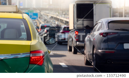 Rear side of taxi sedan car yellow mix green color with turn on brake light. Traffic congestion on the expressway at day time. Heavy traffic conditions in Bangkok Thailand. Rear side of taxi sedan car yellow mix green color with turn on brake light. Traffic congestion on the expressway at day time. Heavy traffic conditions in Bangkok Thailand. 133712490