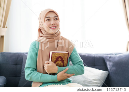 Asian beautiful muslim woman is holding the Holy Koran. Asian beautiful muslim woman is holding the Holy Koran. 133712743