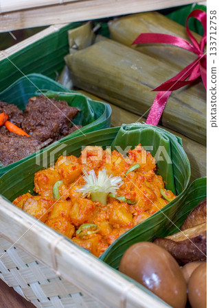 Indonesian Potato Balado, Bacem Eggs, Bacem Tempeh, and Beef Rendang Served in Banana Leaf Containers Inside a Traditional Woven Bamboo Basket, Authentic Southeast Asian Cuisine with Rich Textures and Indonesian Potato Balado, Bacem Eggs, Bacem Tempeh, and Beef Rendang Served in Banana Leaf Containers Inside a Traditional Woven Bamboo Basket, Authentic Southeast Asian Cuisine with Rich Textures and 133712758