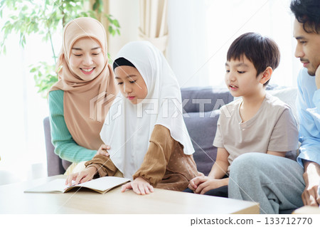 Asian muslim family relaxing in living room together. Asian muslim family relaxing in living room together. 133712770