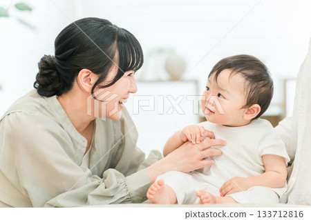 一個年輕的家庭在家裡的客廳沙發上和他們的寶寶一起玩耍。 133712816