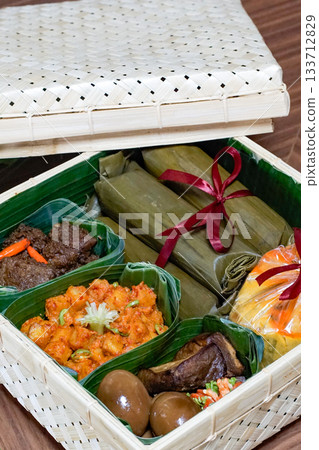 Traditional Indonesian food hamper with lontong wrapped in banana leaf, rendang, kentang balado, bacem eggs and tempe bacem inside a woven bamboo basket Traditional Indonesian food hamper with lontong wrapped in banana leaf, rendang, kentang balado, bacem eggs and tempe bacem inside a woven bamboo basket 133712829