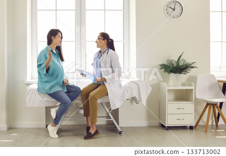 Smiling happy pregnant woman visiting her obstetrician doctor in maternity clinic. 133713002