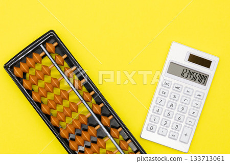 Abacus and calculator on a yellow background 133713061