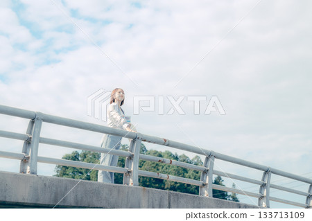 一位二十多歲的女子站在橋上仰望天空的肖像 133713109