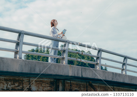 Portrait of a woman in her twenties looking up at the sky on a bridge Portrait of a woman in her twenties looking up at the sky on a bridge 133713110