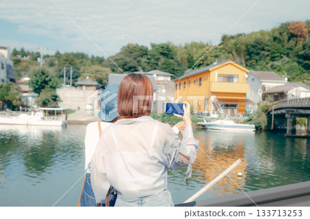 A scene of a senior in his 60s and a woman in her 20s looking at a smartphone while traveling A scene of a senior in his 60s and a woman in her 20s looking at a smartphone while traveling 133713253