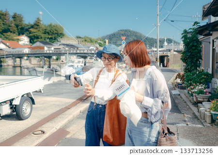 旅途中，一位六十多歲的老人和一位二十多歲的女子正在看智慧型手機。 133713256