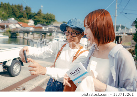 旅途中,一位六十多歲的老人和一位二十多歲的女子正在看智慧型手機。 旅途中,一位六十多歲的老人和一位二十多歲的女子正在看智慧型手機。 133713261