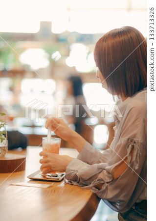 A woman in her twenties enjoying a drink at a cafe A woman in her twenties enjoying a drink at a cafe 133713326