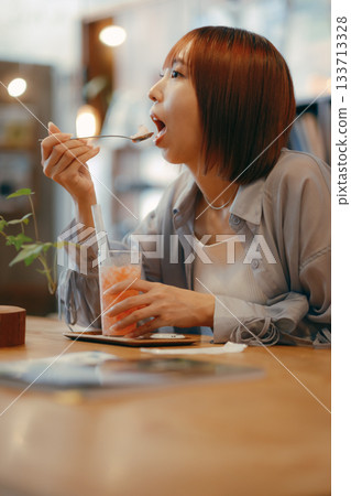 A woman in her twenties enjoying a drink at a cafe A woman in her twenties enjoying a drink at a cafe 133713328