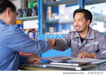 Technician talks with customer in garage. Technician talks with customer in garage. 133713517