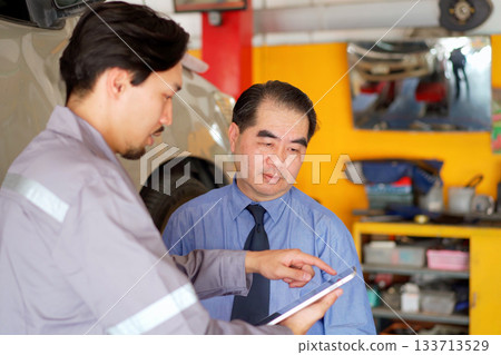 Technician talks with customer in garage. 133713529