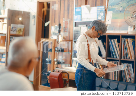A relaxed scene in a store with a couple in their 60s choosing records. 133713729