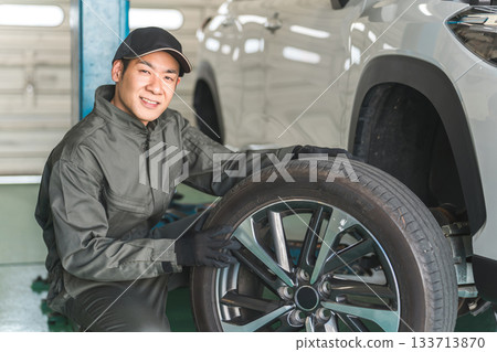 A male mechanic changing a tire on a lifted car A male mechanic changing a tire on a lifted car 133713870