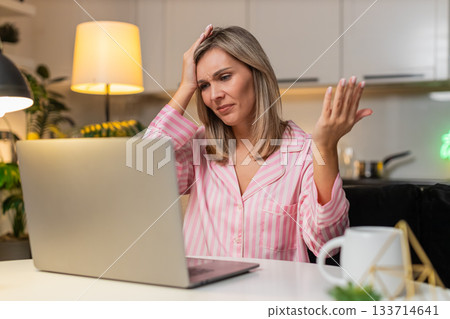 Adult woman freelancer reads tender loss message on laptop frowns shakes head sighs disappointment Adult woman freelancer reads tender loss message on laptop frowns shakes head sighs disappointment 133714641