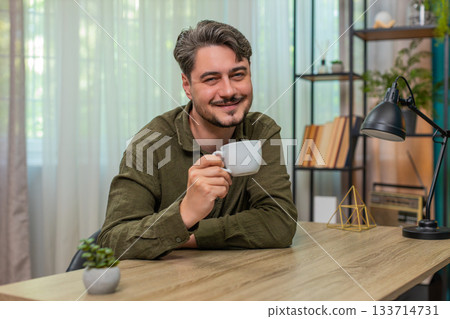 Middle-aged man holding mug enjoys coffee quietly feeling tranquil content relaxation at table desk Middle-aged man holding mug enjoys coffee quietly feeling tranquil content relaxation at table desk 133714731