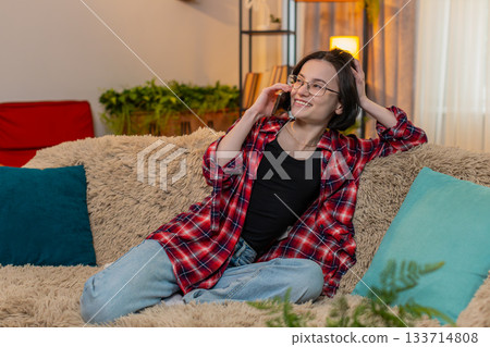 Young woman talking on smartphone, smiling with joy and using expressive hand movement during call 133714808